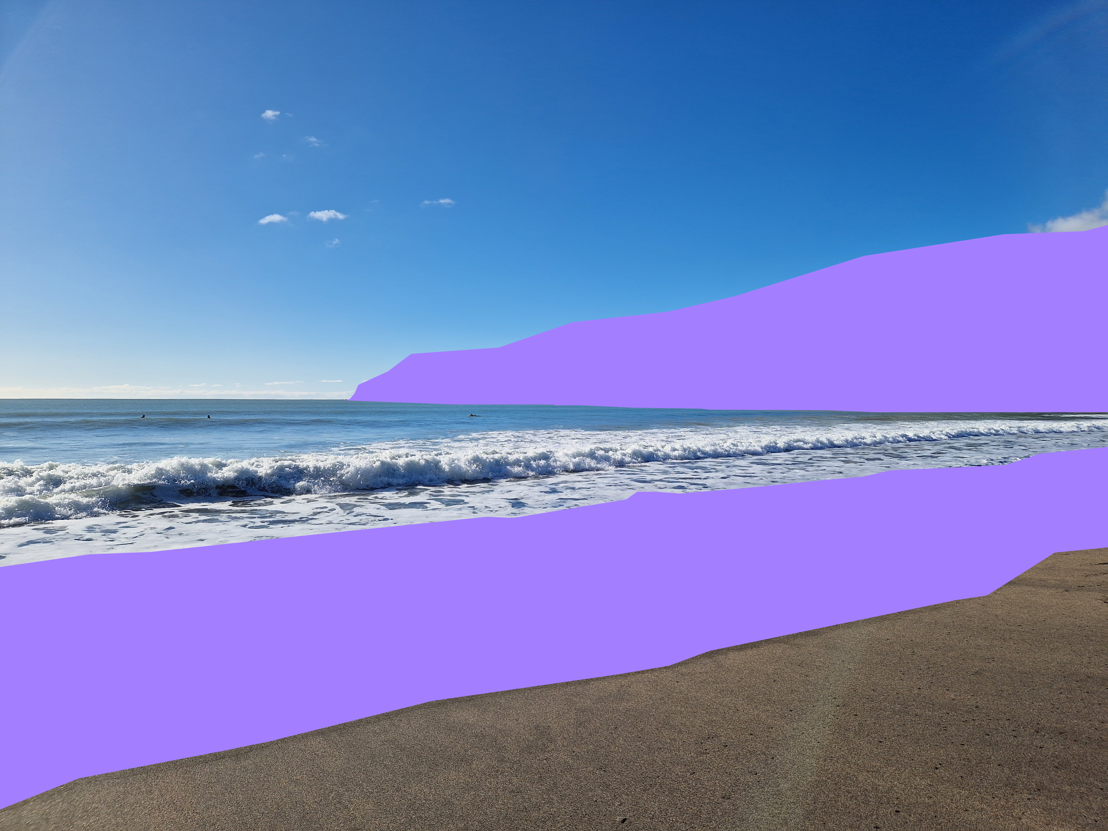 A beach scene with ocean waves, blue sky, and a tan shoreline, with large solid purple overlay blocks covering much of the sky and foreground.